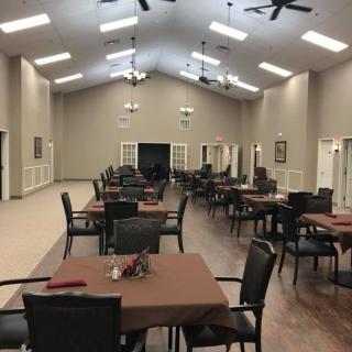 An empty dining hall with neatly arranged tables and chairs.