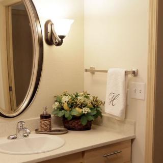 A well-decorated bathroom with a mirror, sink, and floral arrangement.