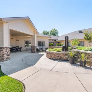 A modern house with a spacious patio and well-maintained garden under clear blue skies.