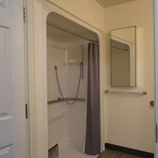 A bathroom featuring a shower with a curtain and a mirror above the sink.
