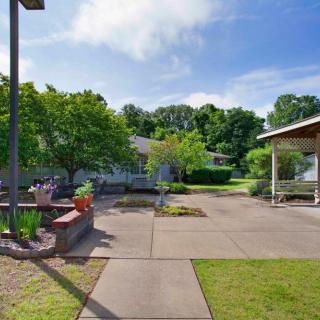 A tranquil outdoor garden with a patio and lush greenery under a clear sky.