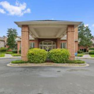 A building entrance with a covered driveway and landscaped greenery.
