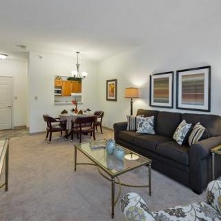 A cozy living room with a sofa, coffee table, dining area, and decorative artwork on the walls.