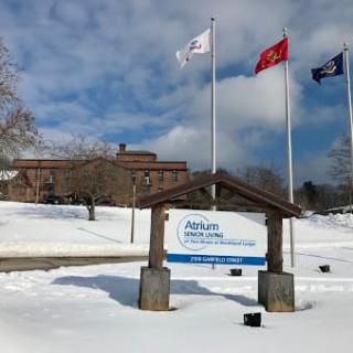 A snowy landscape featuring a building with three flags and a sign for Atrium Health's Carolinas Rehabilitation.