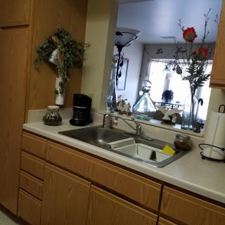 A kitchen with wooden cabinets, a sink, and various appliances and decorations.