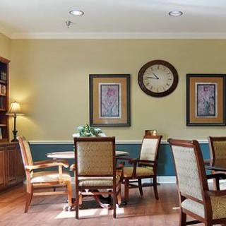 A cozy dining area with a table and chairs, adorned with wall art and a clock.