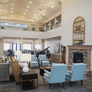 A spacious and elegantly designed living room featuring modern furniture, a grand piano, and a cozy fireplace.