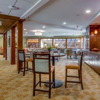 A cozy interior of a restaurant with a dining area and bar, featuring comfortable seating and warm lighting.