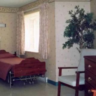 A clean hospital room with a bed, chair, and curtains by the window.