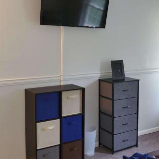 A room with a wall-mounted television, cube storage units, and a set of drawers.