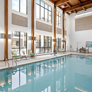 A modern indoor swimming pool area with large windows and wooden beams.