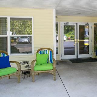 A cozy entrance area with wicker chairs and colorful cushions.