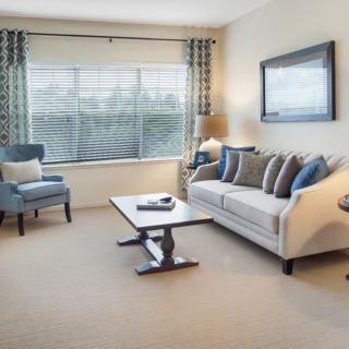 A cozy and modern living room with a sofa, armchair, and coffee table near a large window.