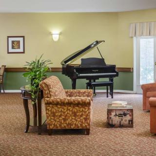 A cozy living room with a grand piano and comfortable seating arrangements.