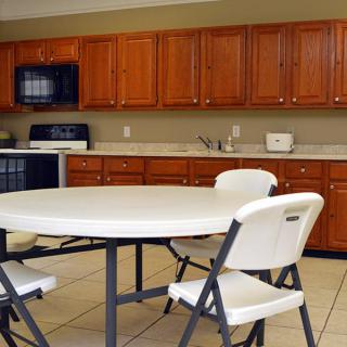 A kitchen with wooden cabinets, a round table, and folding chairs.