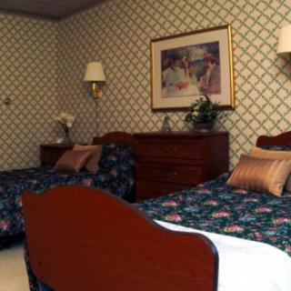 A bedroom with twin beds, floral bedspreads, and patterned wallpaper.