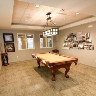 A cozy billiard room with a classic pool table, stylish lighting, and vintage wall decor.