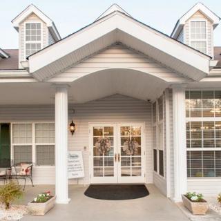 A residential building entrance with white columns and large windows.