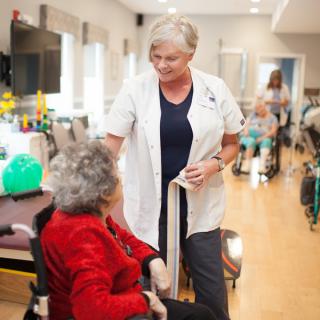 A caregiver interacting with an elderly woman in a nursing home setting.