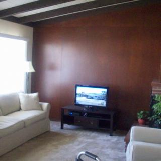 A cozy living room with a sofa, television, lamp, and wood panel wall.