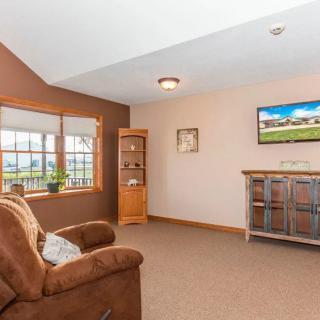 A cozy living room with a brown armchair, a large window, and decorative elements including a cabinet and a painting.