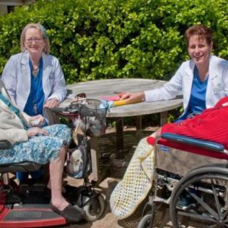 A group of elderly individuals and caregivers enjoying time outdoors in a park setting.