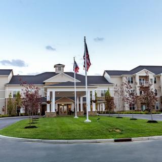 A large building with an elegant entrance, featuring flags and a well-maintained lawn in front.
