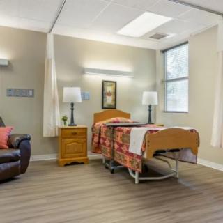 A well-lit hospital room featuring a bed, comfortable seating, and various furnishings.