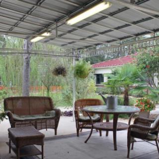 A cozy outdoor patio with seating and plants in a garden setting.