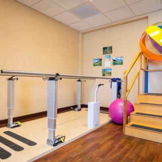 A well-equipped rehabilitation area featuring a balance bar, exercise balls, and stairs for physical therapy.