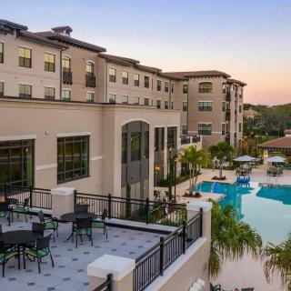 A modern hotel with a beautiful pool area and outdoor seating at sunset.