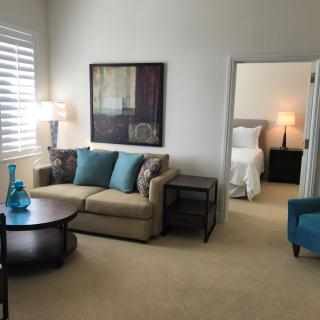A cozy living room with a sofa and coffee table, adjacent to a bedroom.