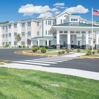 A well-maintained hotel or residential building with a landscaped entrance and an American flag.