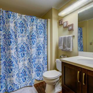A neatly arranged bathroom with a blue patterned shower curtain and wooden vanity.