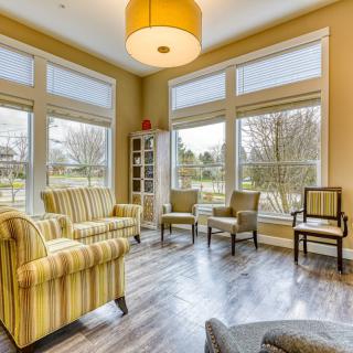 A cozy living room with striped armchairs and large windows letting in natural light.