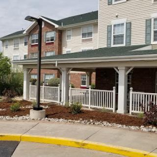 A view of a residential building featuring a covered porch and landscaped surroundings.
