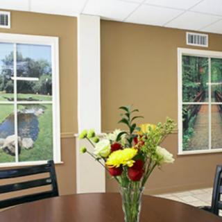A room with decorative artificial windows and a table centerpiece with flowers.