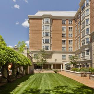 A well-maintained garden area in front of a multi-story brick building under a clear blue sky.
