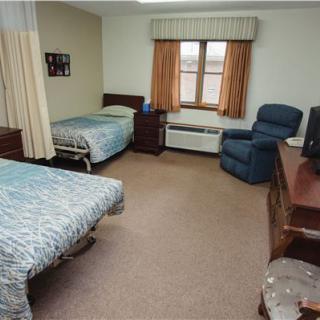 A cozy bedroom with two beds, a recliner, and a window with curtains.