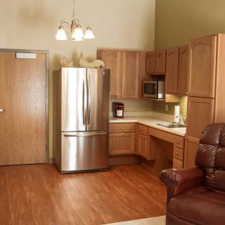 A modern kitchen with wooden cabinets, a stainless steel refrigerator, and microwave.