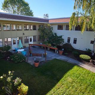 A sunny courtyard surrounded by a building with a garden area.