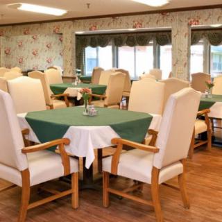 A cozy dining area with tables covered in green tablecloths and comfortable chairs.