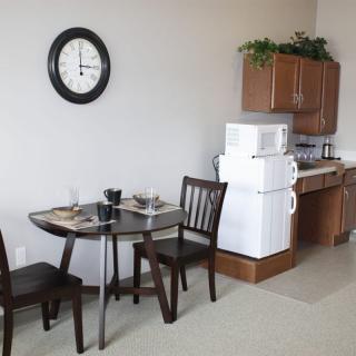 A small kitchen and dining area with a table, chairs, microwave, and refrigerator.