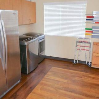 Modern laundry room with appliances and wooden flooring.