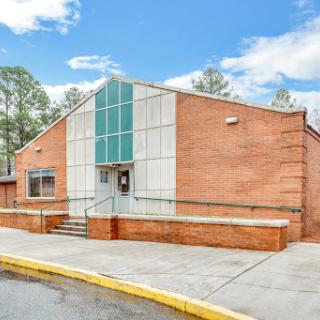 A modern brick building featuring a distinctive angular design and surrounded by a bright blue sky.