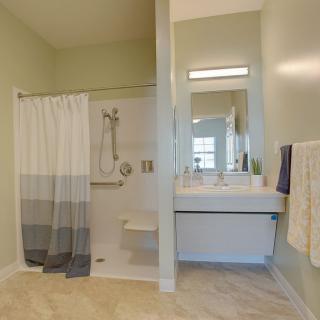 A modern bathroom featuring a shower with a curtain, a wall-mounted sink, and a large mirror.