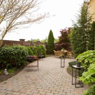 A beautifully landscaped garden with a paved patio and outdoor furniture.