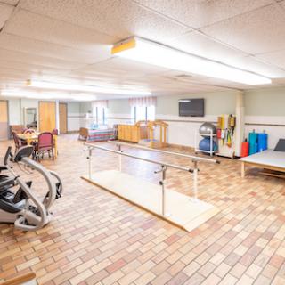 A spacious rehabilitation center equipped with exercise machines, walking bars, and a comfortable environment for physical therapy.