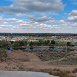 A panoramic view of the landscape showcasing rolling hills and a blue sky dotted with clouds.