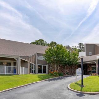 A building with a driveway and landscaped surroundings under a clear sky.